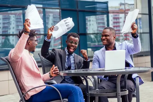 Three business professionals celebrating success with paperwork outside an office